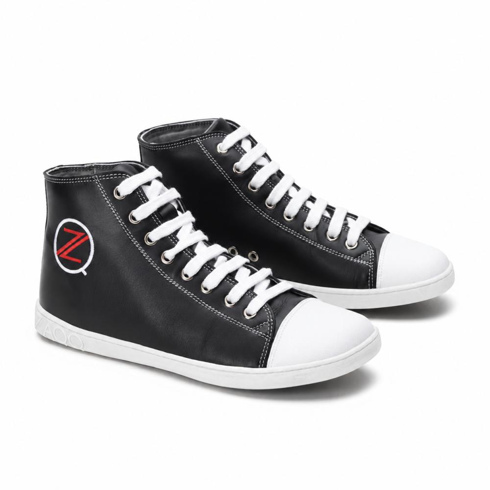Egy pár klasszikus fekete magas szárú ZAQQ CHUQQS sneaker fehér cipőfűzővel és orrvédővel rendelkezik, amelyeken egy feltűnő piros-fehér Z-logó látható. A talpak tartós gumiból készülnek, ami trendi, enyhén kopott megjelenést kölcsönöz a cipőknek.