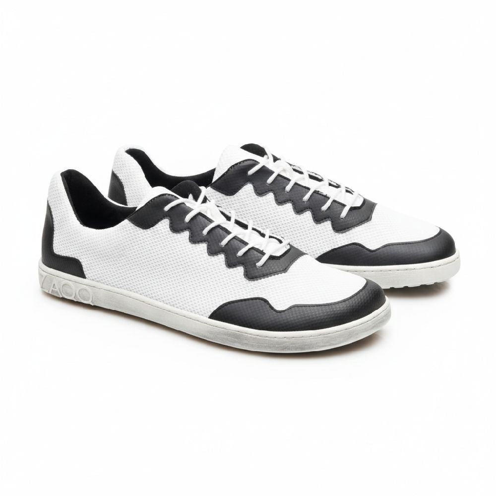 Wir präsentieren die DUPLEQ Black White Vegan Sneaker von ZAQQ: Diese stylischen schwarz-weißen Schuhe haben weiße Schnürsenkel und Sohlen und sind mit einem strukturierten Muster aus atmungsaktivem Meshgewebe gestaltet. Ein Logo ziert die Ferse und verleiht diesen veganen Barfußschuhen ein schlichtes Aussehen, da sie nebeneinander auf einem schlichten weißen Hintergrund stehen.