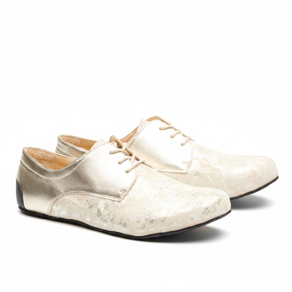 Bei den Schuhen IQON Gold von ZAQQ handelt es sich um einen beige-goldenen Derby-Schnitt mit Schnürung und leicht glänzendem Finish, der durch ein Strukturmuster besticht. Die schwarze Sohle bietet einen markanten Kontrast zum hellen Obermaterial und ist somit ideal für ein elegantes Business-Outfit. Die Schuhe werden nebeneinander auf einem schlichten weißen Untergrund präsentiert.