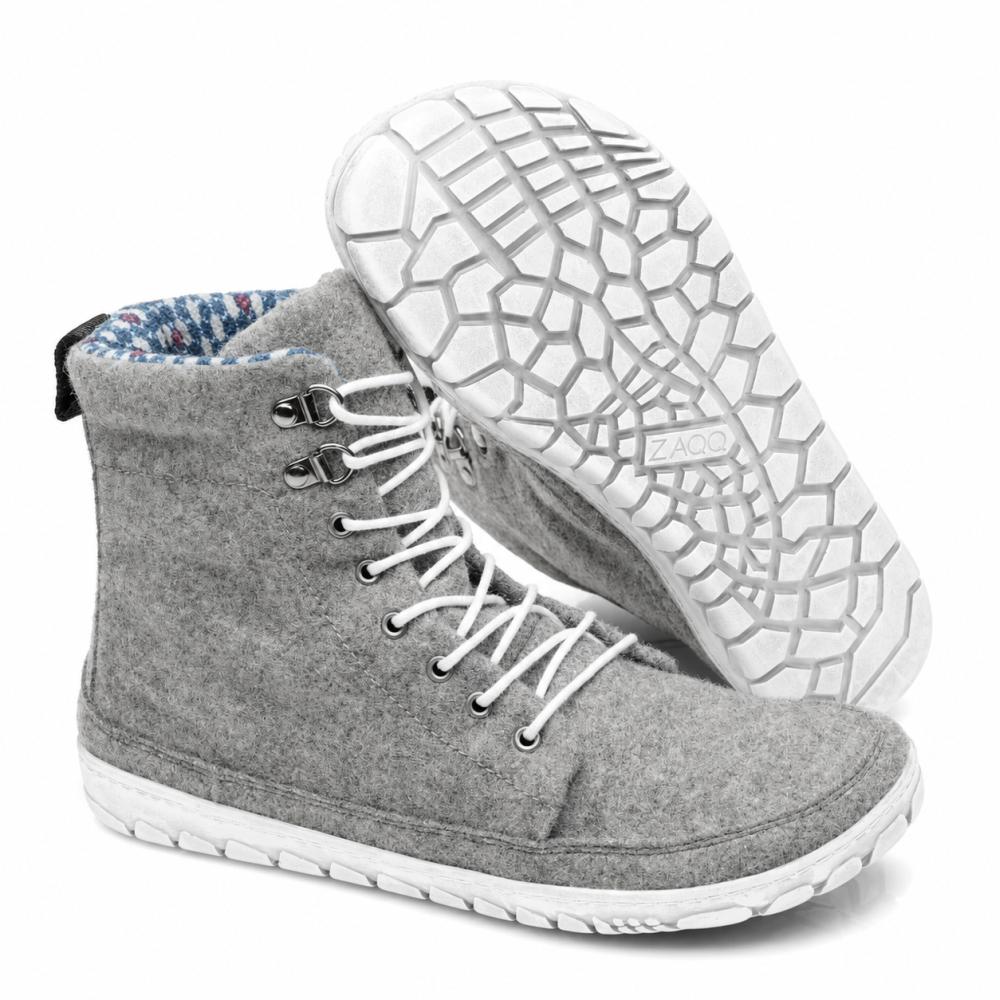 Bemutatásra kerül egy pár ZAQQ QICE Grey magas szárú sneaker fehér fűzőkkel. Az egyik cipő álló helyzetben van, míg a másik meg van döntve, hogy kiemelje a strukturált, mintás kültéri talpat.