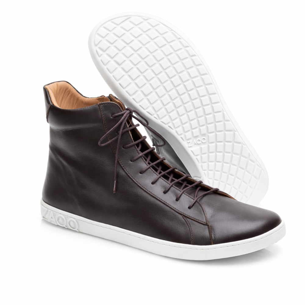 Ein Paar schicke SNAQ High-Top-Sneaker aus dunkelbraunem Nappaleder mit weißer Sohle. Ein Schuh steht aufrecht und zeigt seine Seite, während der andere auf der Seite liegt und das strukturierte Muster der Sohle zeigt. Auf der Unterseite ist der Markenname ZAQQ zu sehen.